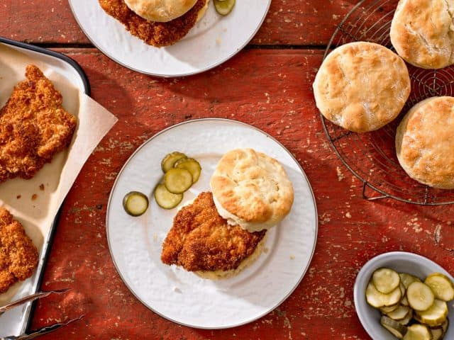 Top down view of Cold Fried Chicken and Biscuits with pickles on red wood table