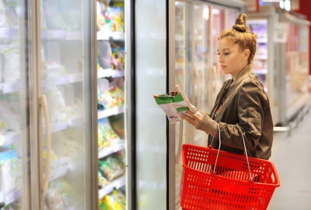 Woman choosing frozen food from a supermarket freezer