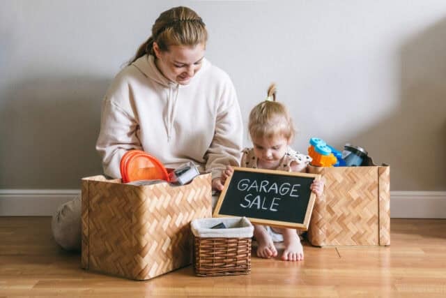 A young woman and her daughter packed up for a garage sale and donation. Box with the words "Garage Sale"