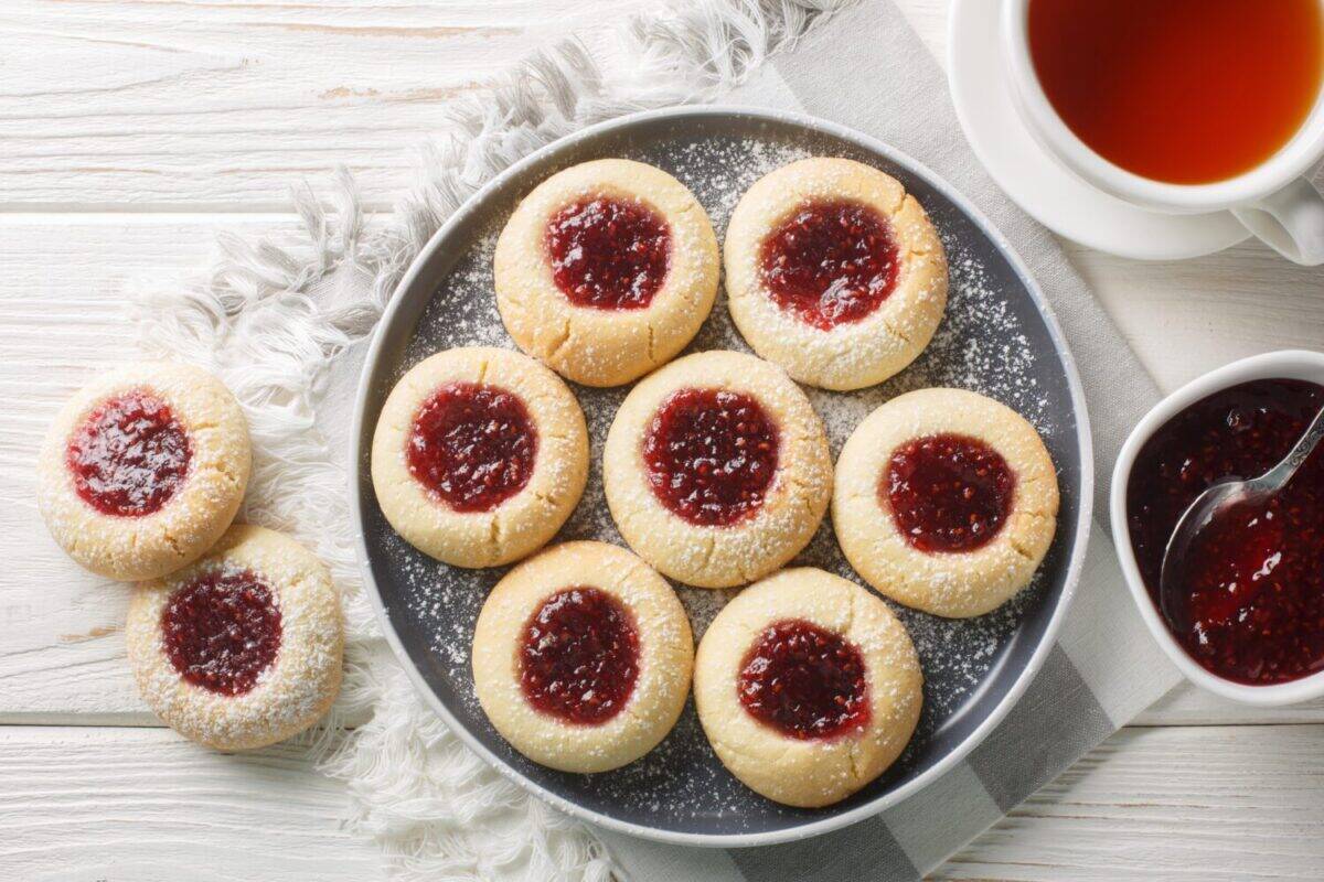 Hallongrottor Swedish Thumbprint Cookies closeup on the plate on the white wooden table. Horizontal top view from above