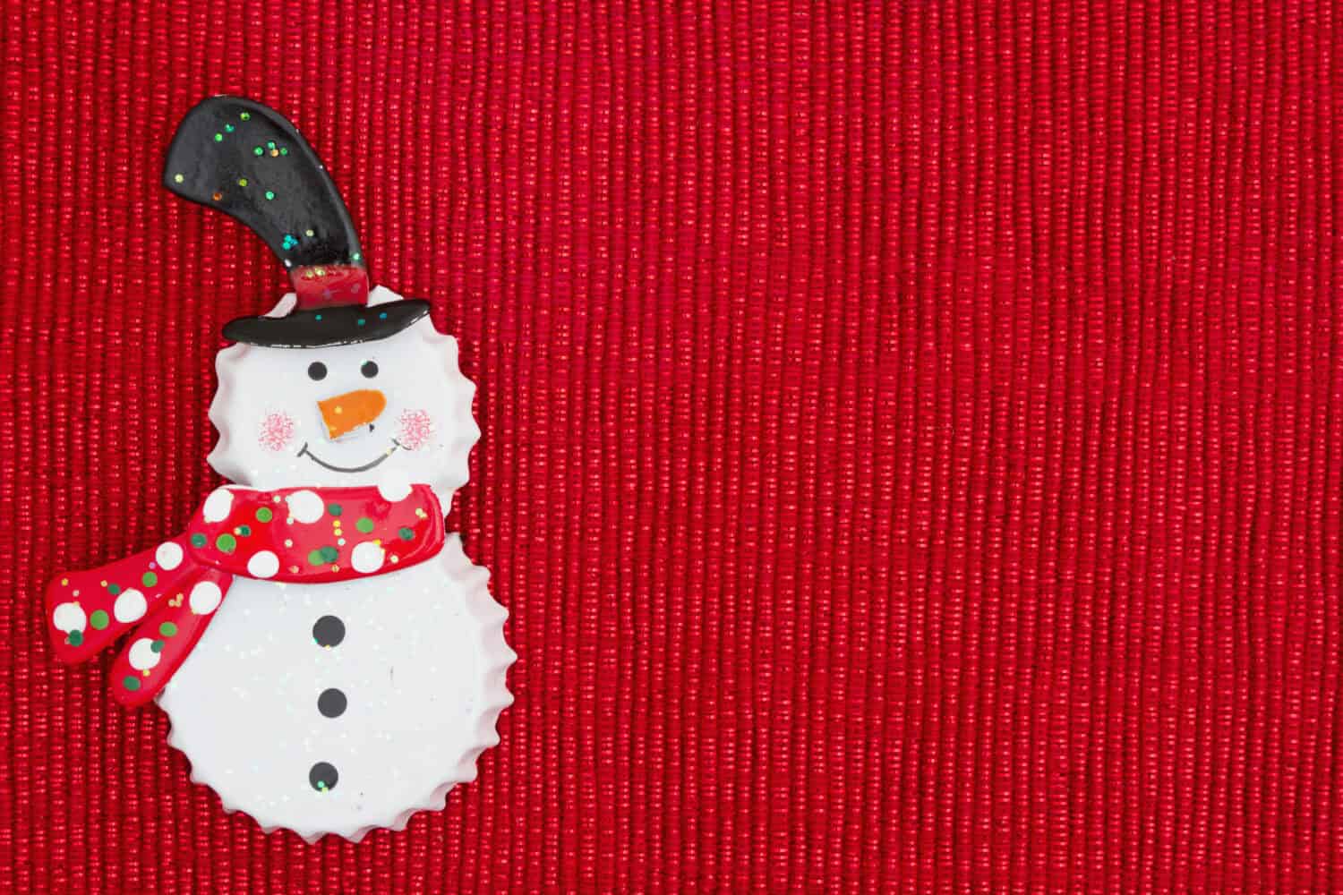 Christmas time background, Bottle cap snowman on a shiny red background with copy space for your message
