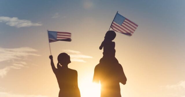 Patriotic silhouette of family waving American USA flags.