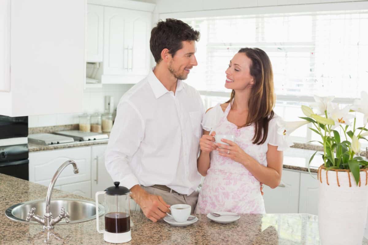 Happy young couple having coffee in the kitchen at home