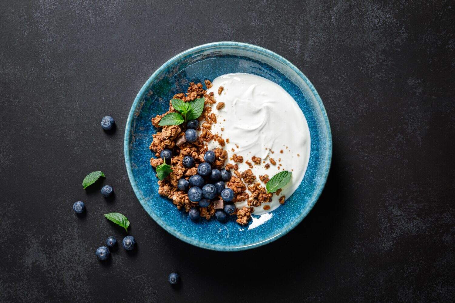 Chocolate granola with white plain yogurt and fresh blueberry in a bowl, healthy food for breakfast, top view