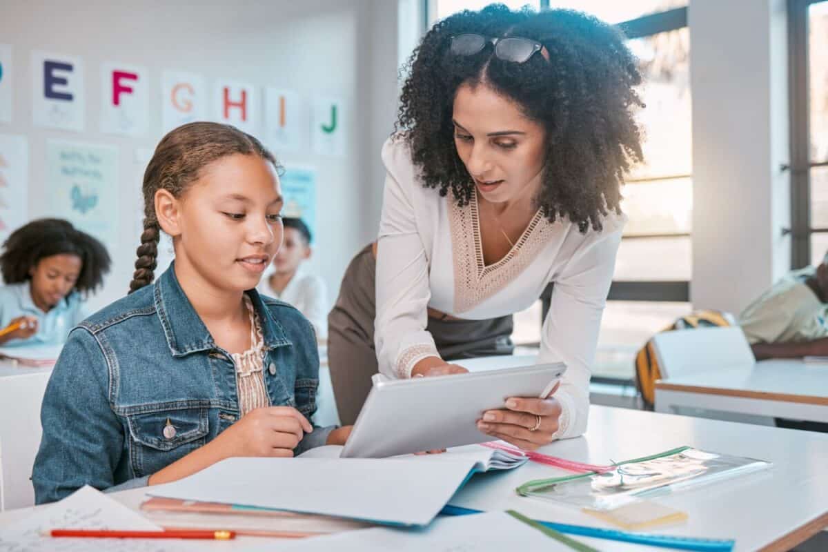 Education, tablet or girl students with teacher for ebook learning, assessment idea or scholarship research. Consulting, school or kid in classroom for information help, collaboration or search