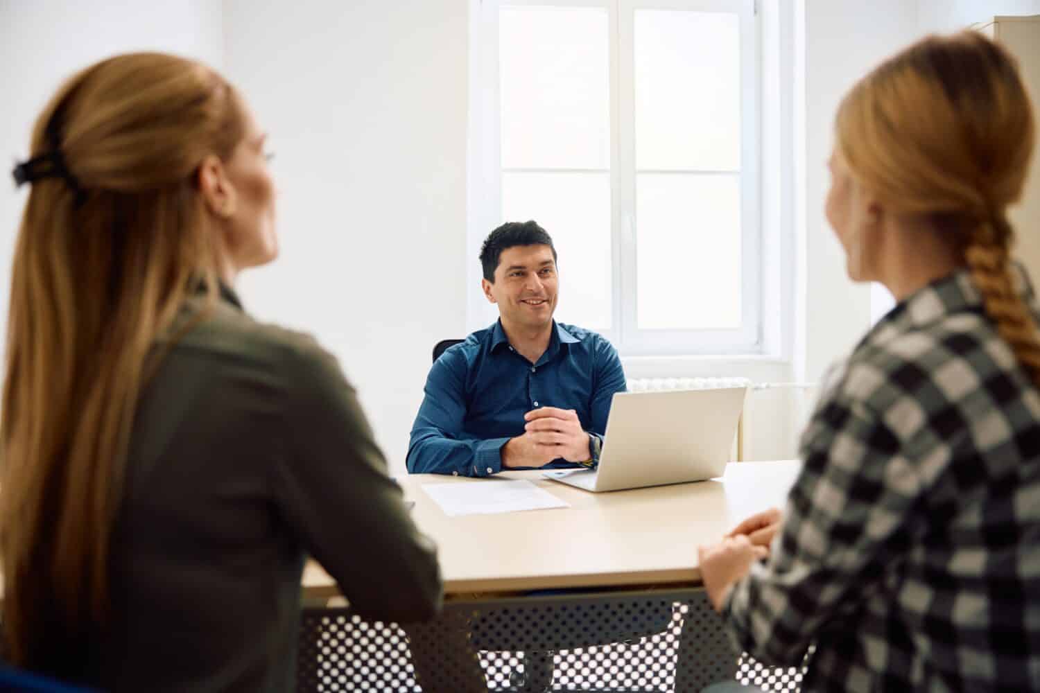 Happy principal communicating with mother and daughter about admission to high school.