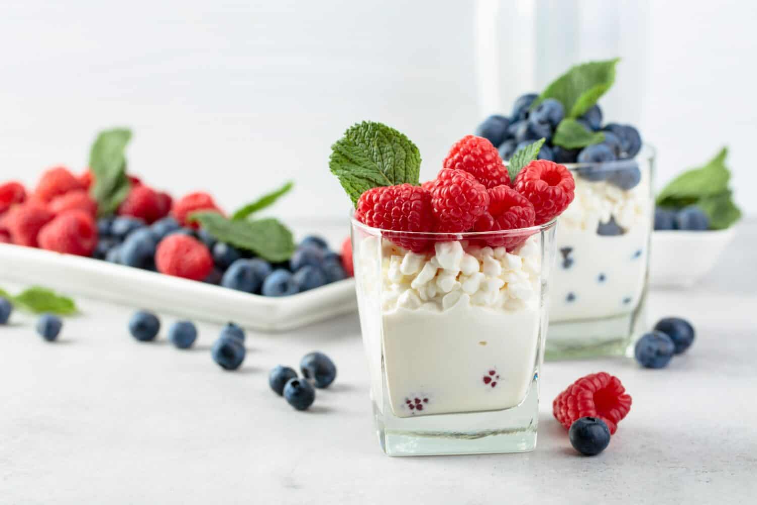 Cottage cheese with cream, raspberries, and blueberries garnished with fresh mint. 