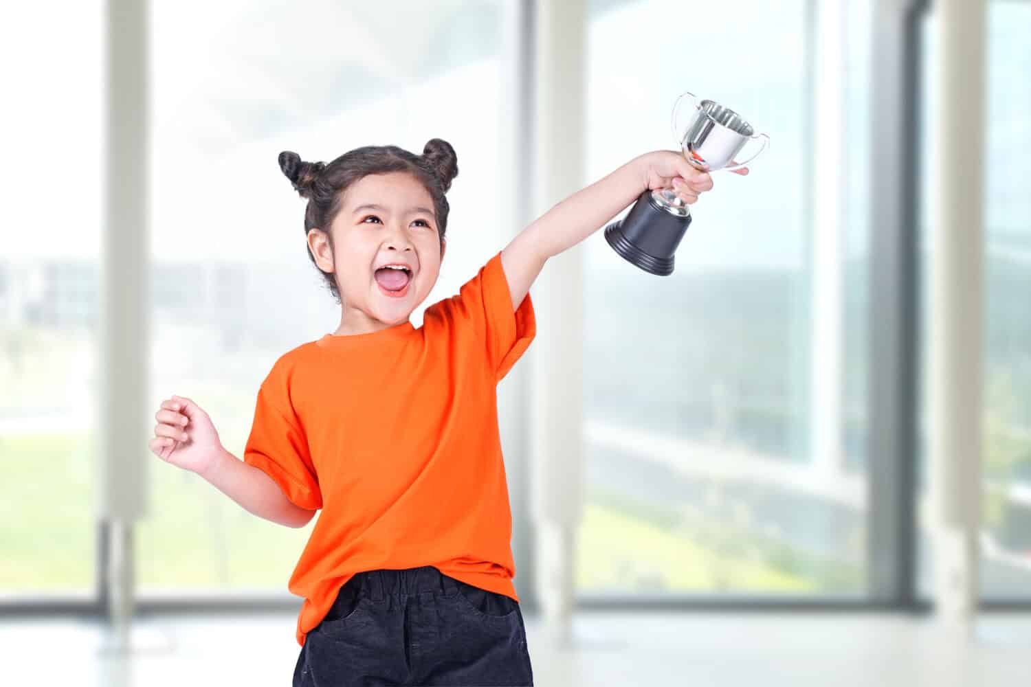 Asian Little Chinese Girl Smiles with a Trophy in Her Hands