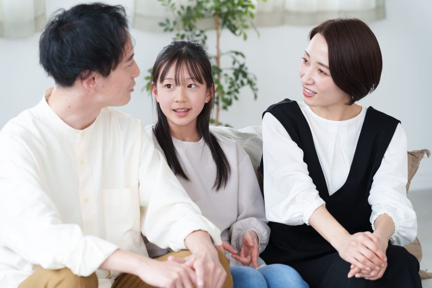 young asian family relaxing in living room,sitting on sofa,talking to each other.
