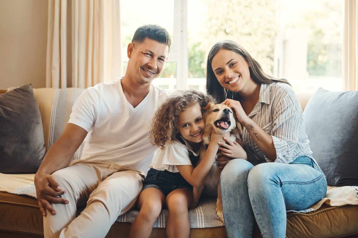 Mother, father and girl with dog for portrait on sofa for love, bonding and affection with safety or animal. Mom, dad and kid with family pet in home with care, together and relax with happiness.
