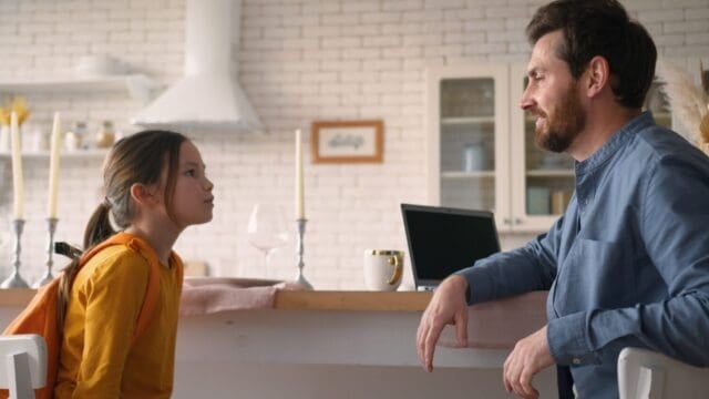 Caucasian guy man parent using laptop work happy kid daughter pupil running return home after school education smiling male father meet little girl schoolgirl dad embracing kiss child speaking family