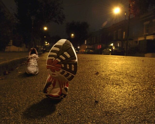 Empty running shoes jogging on city street at night