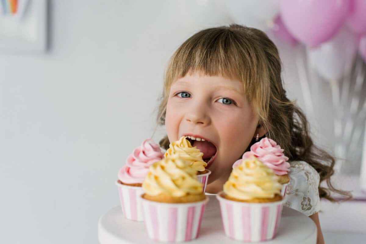 close up portrait of adorable birthday child eating cupcakes