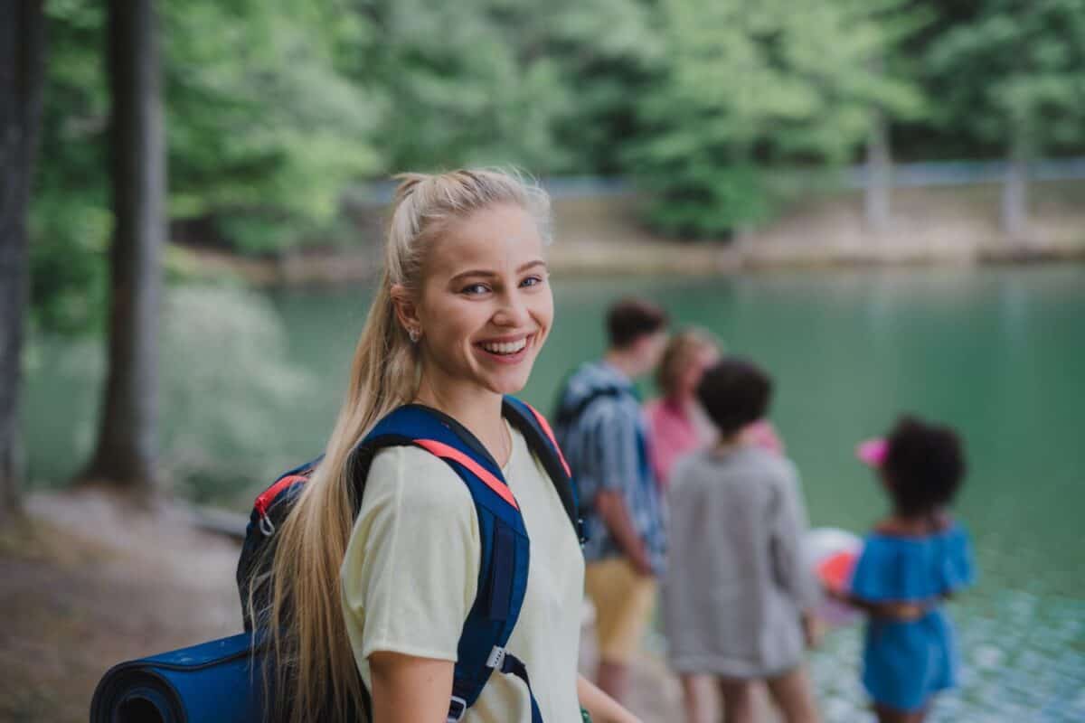 Young woman with friends on a hiking or camping trip in the mountains in summer.