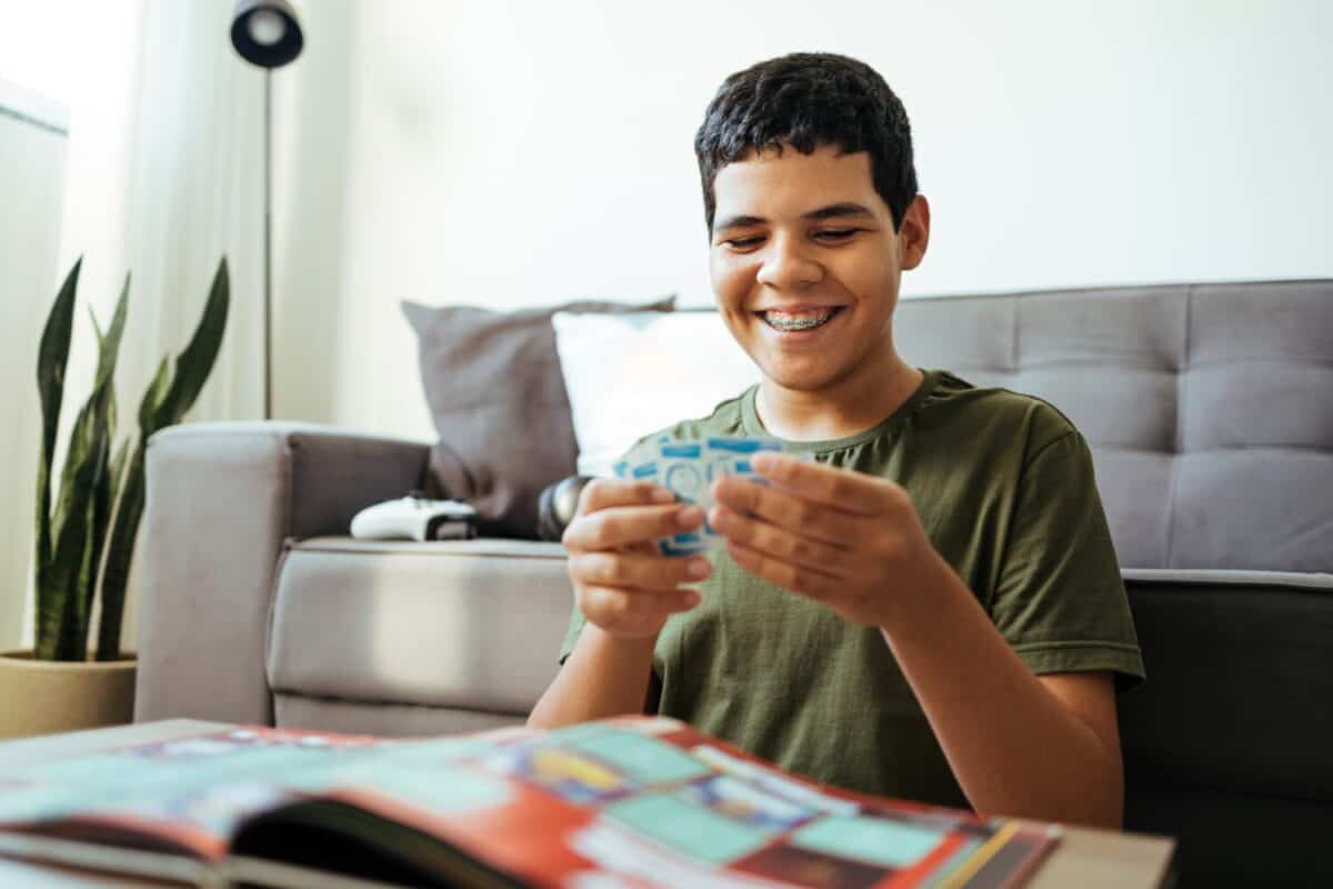 Teen boy pasting stickers in collection album for world football championship
