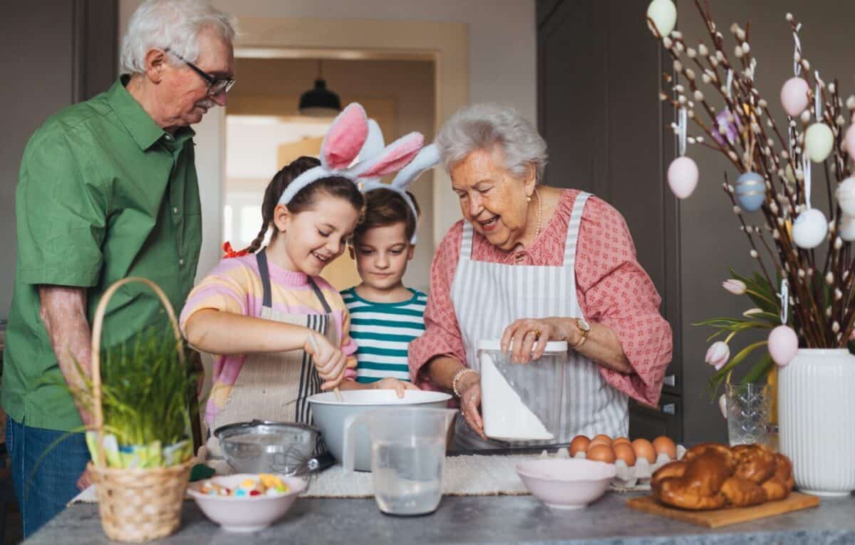 Grandparents with grandchildren preparing traditional easter meals, baking cakes and sweets. Passing down family recipes, custom and stories.