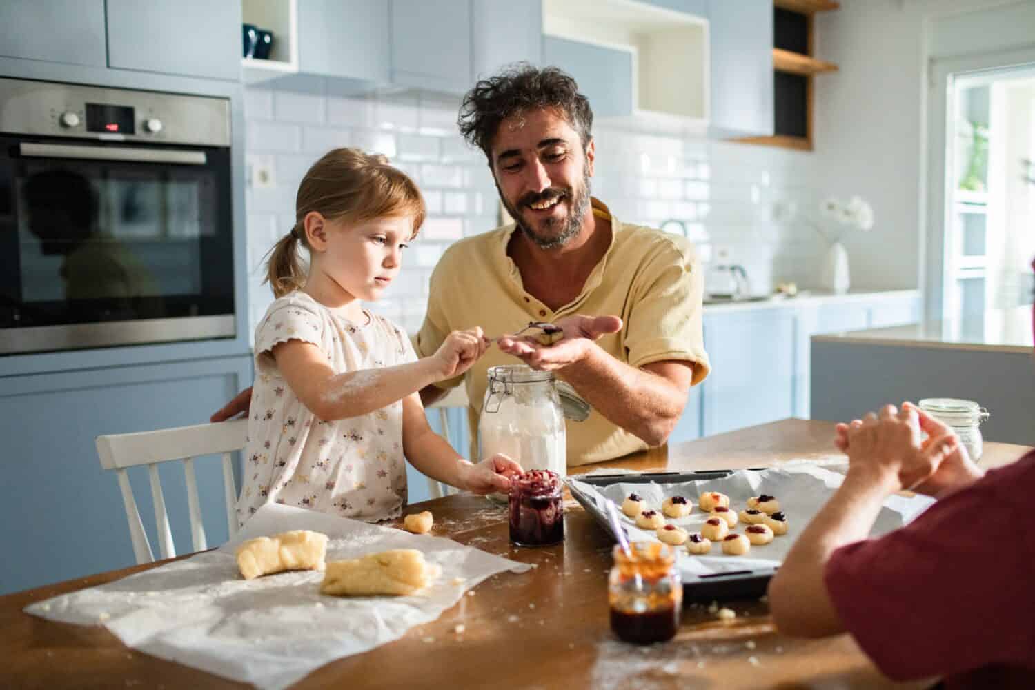 Father and daughter baking together in kitchen with playful expressions