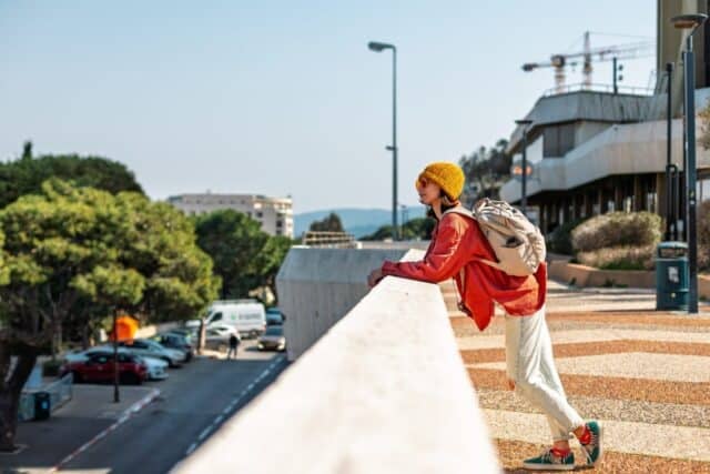Happy girl with camera walks around the city. Young tourist sightseeing and walking around the city. Tourist walking around the city.