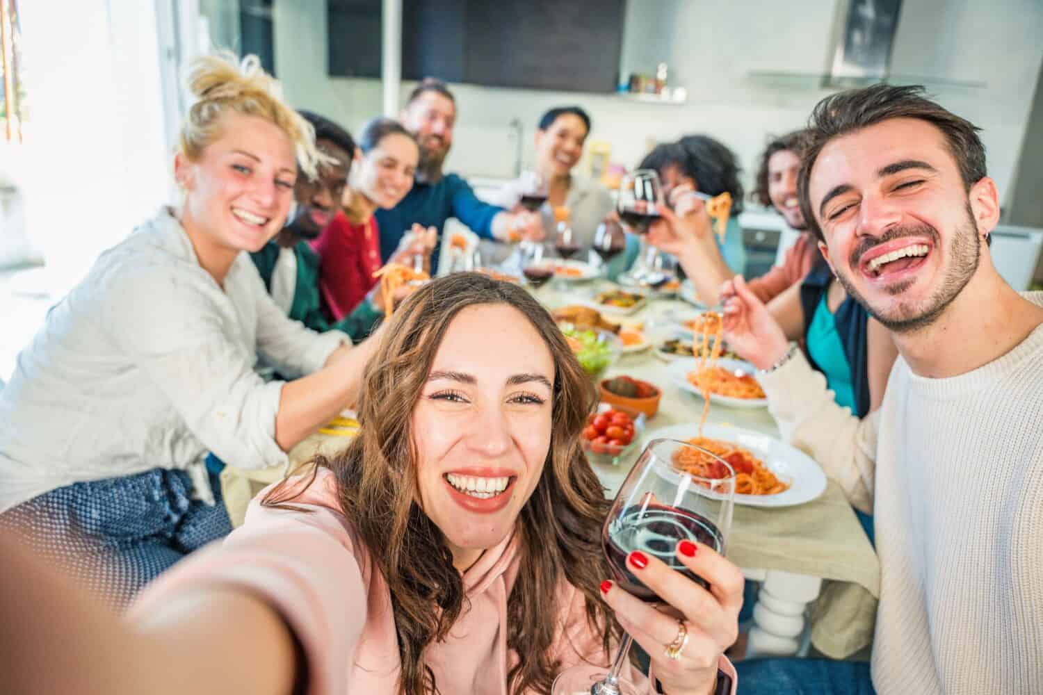 Happy group of friends having dinner party at home - Cheerful young people having lunch break together - Life style concept with guys and girls celebrating thanksgiving - Food and beverage lifestyle