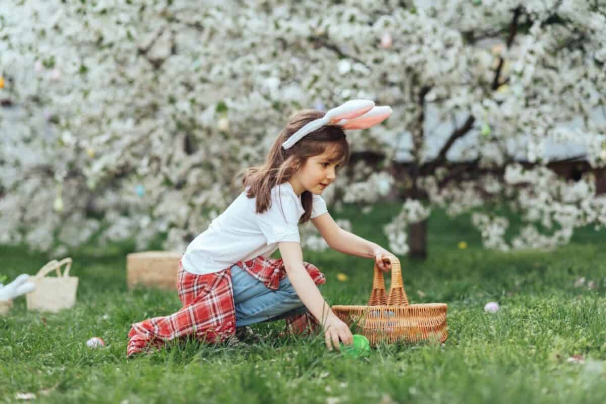 Portrait of happy child holding Easter basket on easter egg hunt. Joyful outdoor family moment celebrating Easter, childhood, and seasonal traditions.