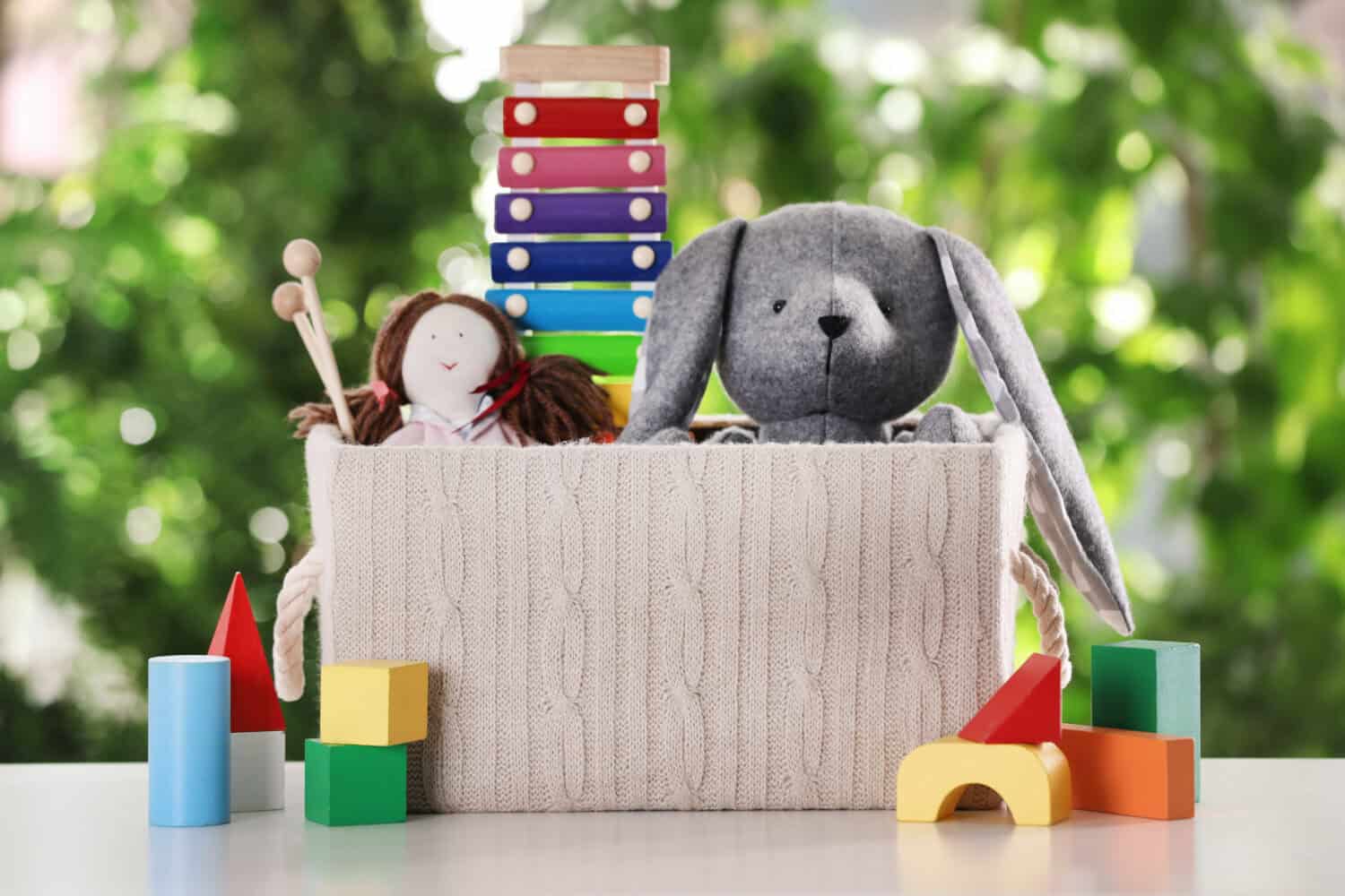 Box and different toys on table against blurred background