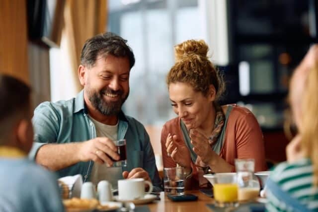 Happy parents having fun while eating breakfast with their kids in a restaurant.