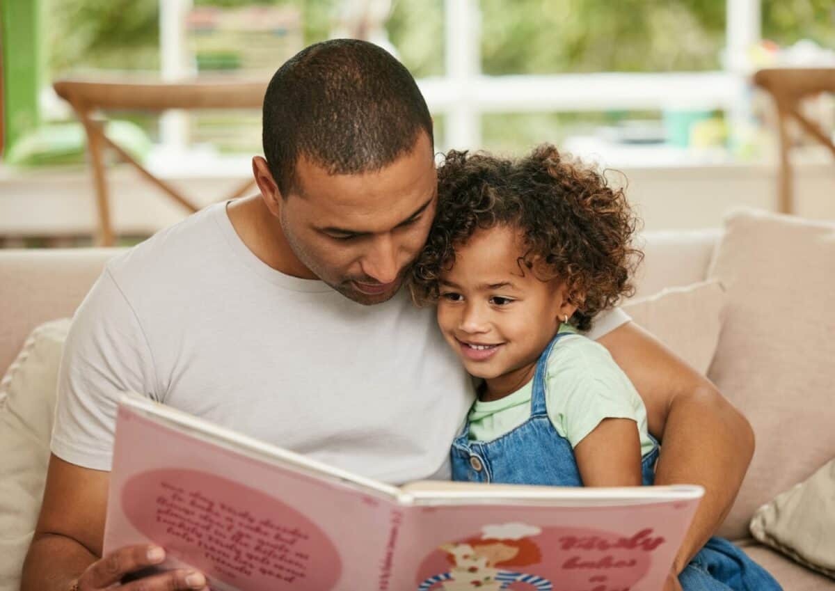 Father, girl child and reading book in home for family bonding, learning and development in lounge. Dad, kid and together on sofa for storytelling with fairytale, parent teaching for childhood growth