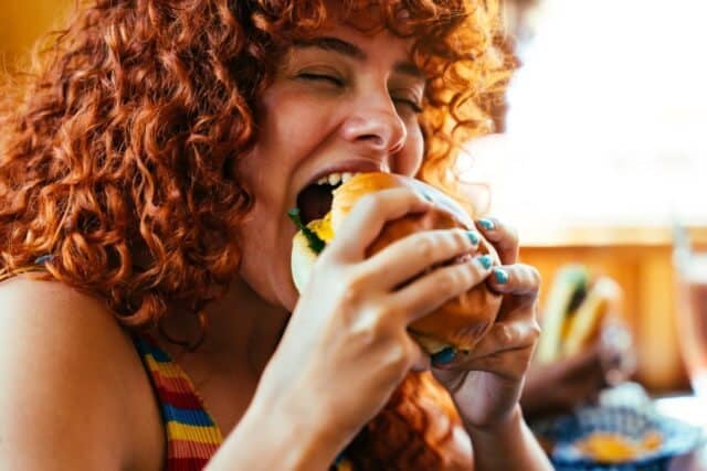 Multiethnic group of friends having meal at 80s vintage diner restaurant - Multiracial young people bonding and having fun, eating in an american fast food burger house