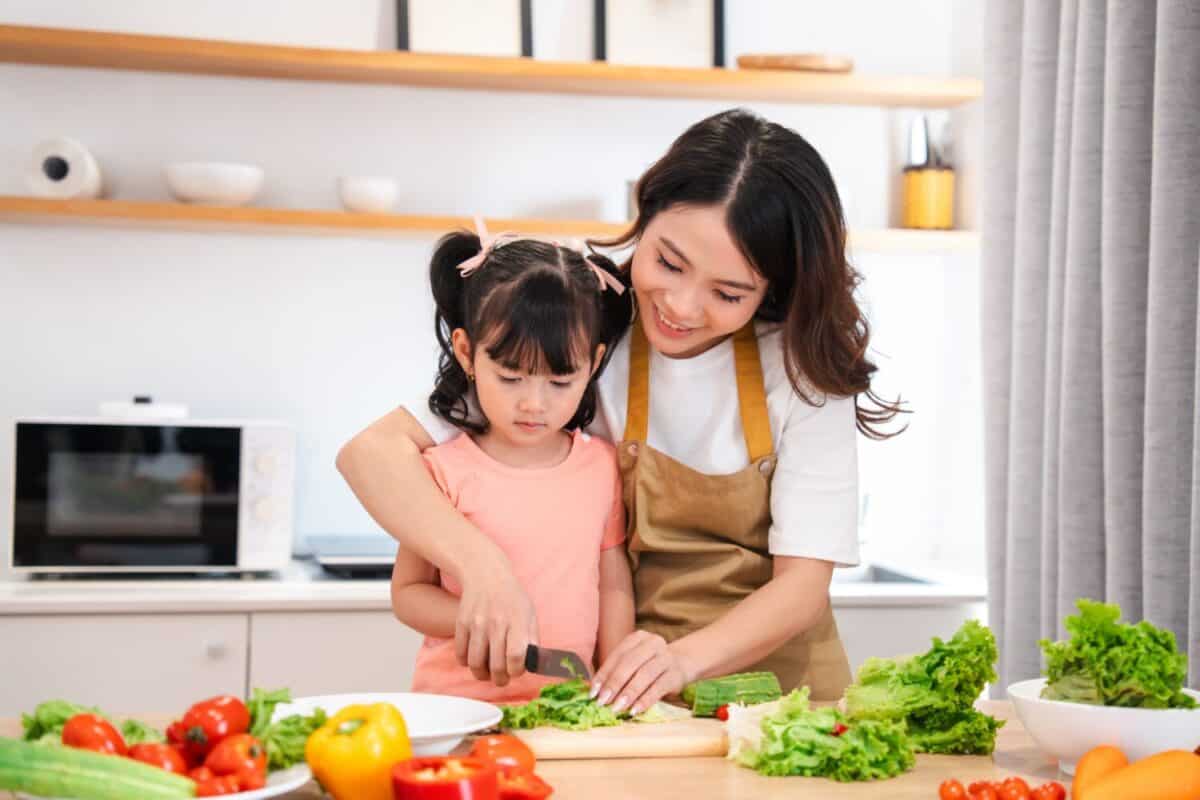 Mother and Daughter Prepare a Salad Together in Kitchen Learning to Cook Healthy Eating