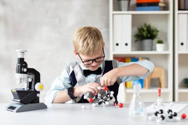 Cute child in casual clothes assemble a model of a chemical element
