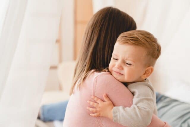 Caucasian mother lulling cradling her crying little small son daughter toddler infant newborn baby. Colics, teething health problems. Postnatal depression. Motherhood and childcare