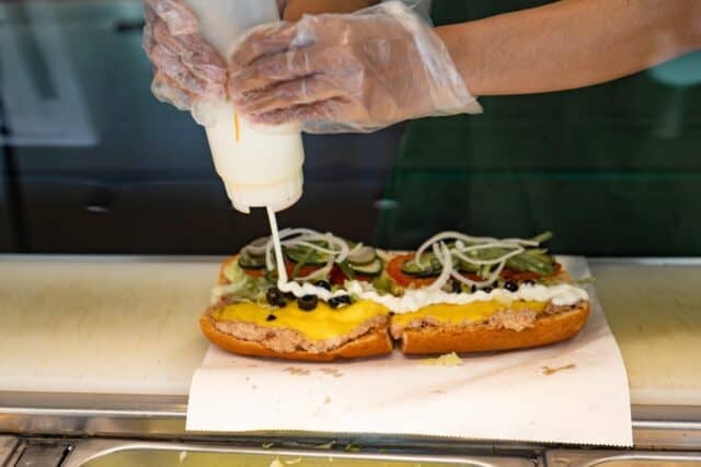 Here's a waiter preparing a sandwich ordered by a customer at a Subway fast food restaurant.