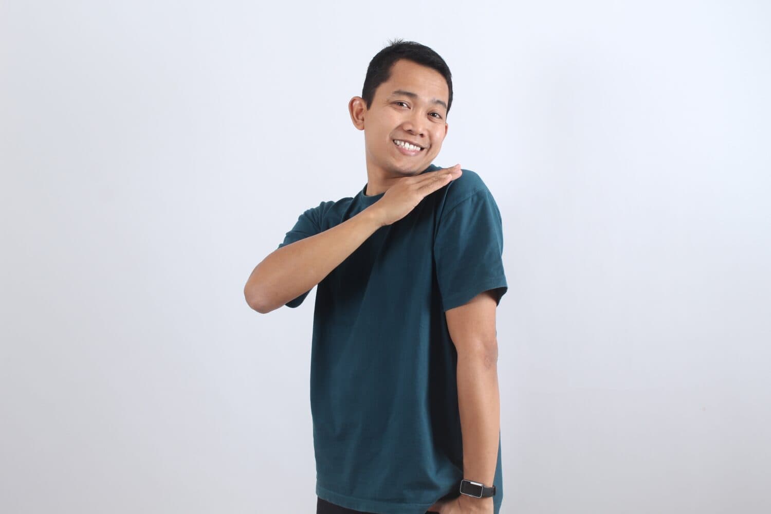 Portrait of a cheerful young Asian man smiling with confidence. A friendly guy shows pride and satisfaction with a positive gesture on a grey background.
