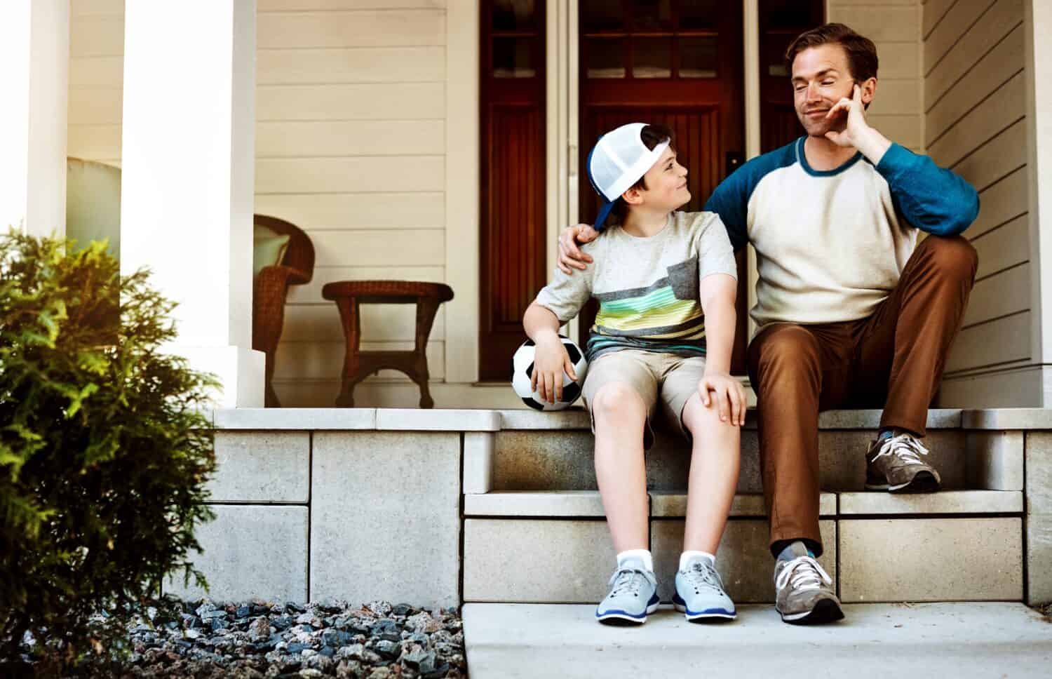 Soccer ball, outdoor and dad with child for bonding, sports or conversation together. Happy, talking and father with boy kid on steps in backyard for connection, support and advice on training.