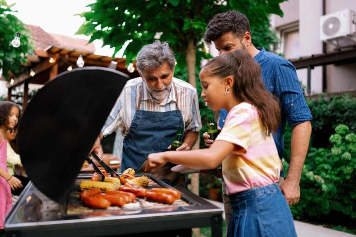 Grandfather Serving Food to Granddaughter at Family Barbecue