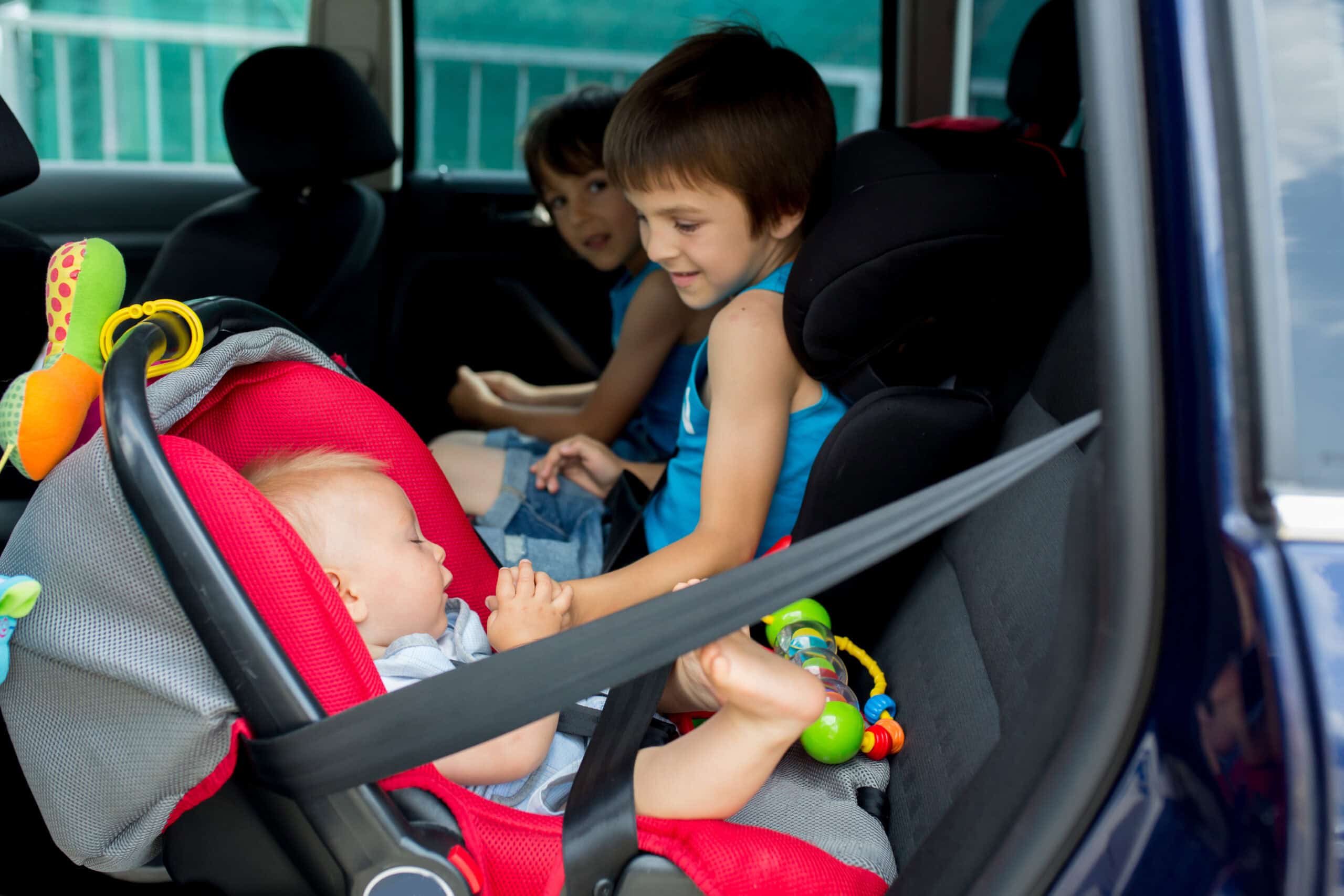 Little baby boy and his older brothers, traveling in car seats, going on a holiday, traveling on the back seat