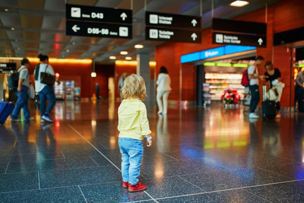 Adorable little girl alone in the airport. Lost toddler looking for parents. Travelling with small kids