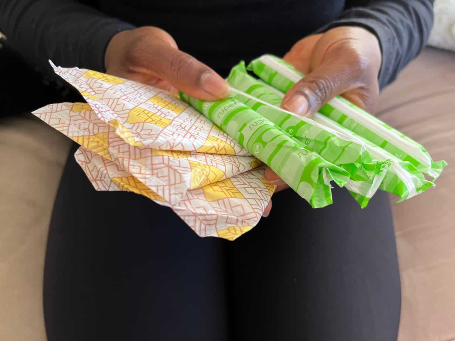 Concept image of a Black person holding tampons and pads