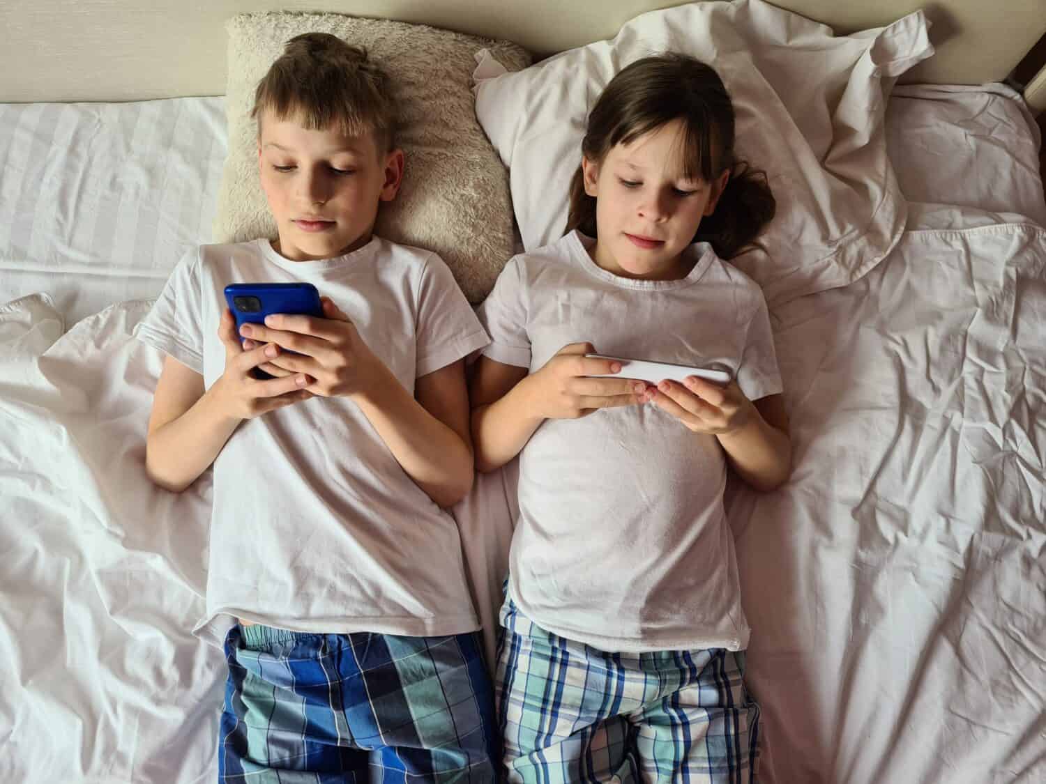 Children of different ages bed with different electronic gadgets concept