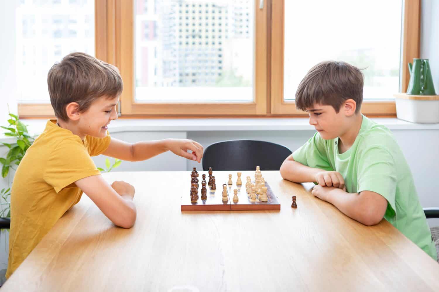 Two brothers are having fun at home playing chess
