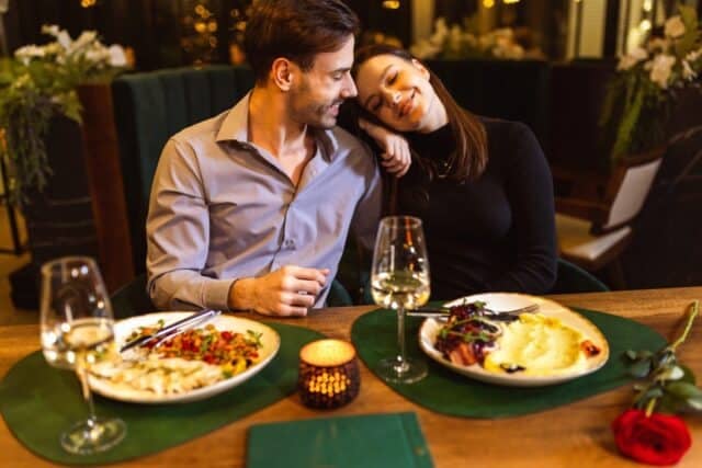 Happy couple having romantic dinner date in a fancy restaurant. They eat delicious dishes.