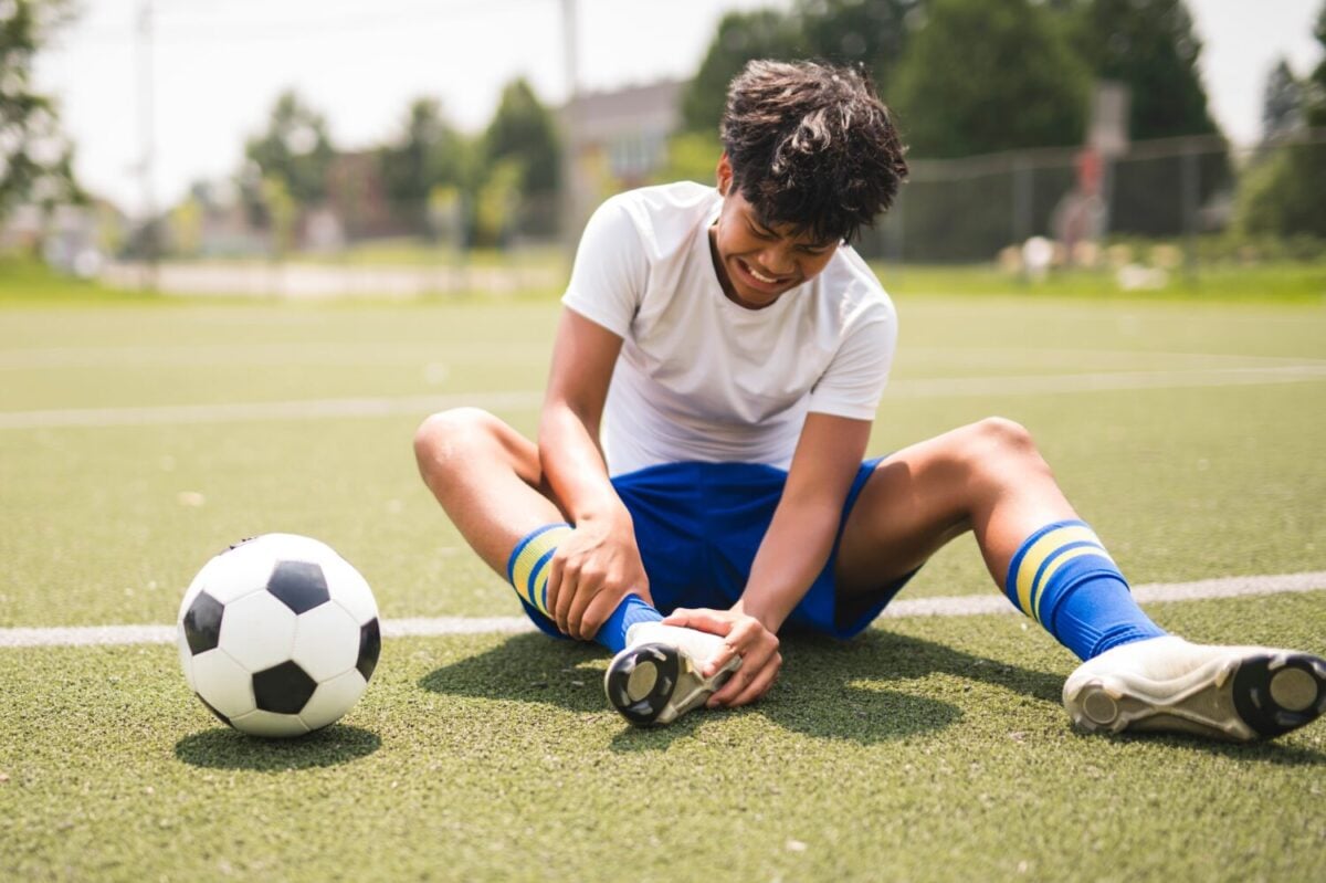 A nice Boy with soccer ball outside on field having injury