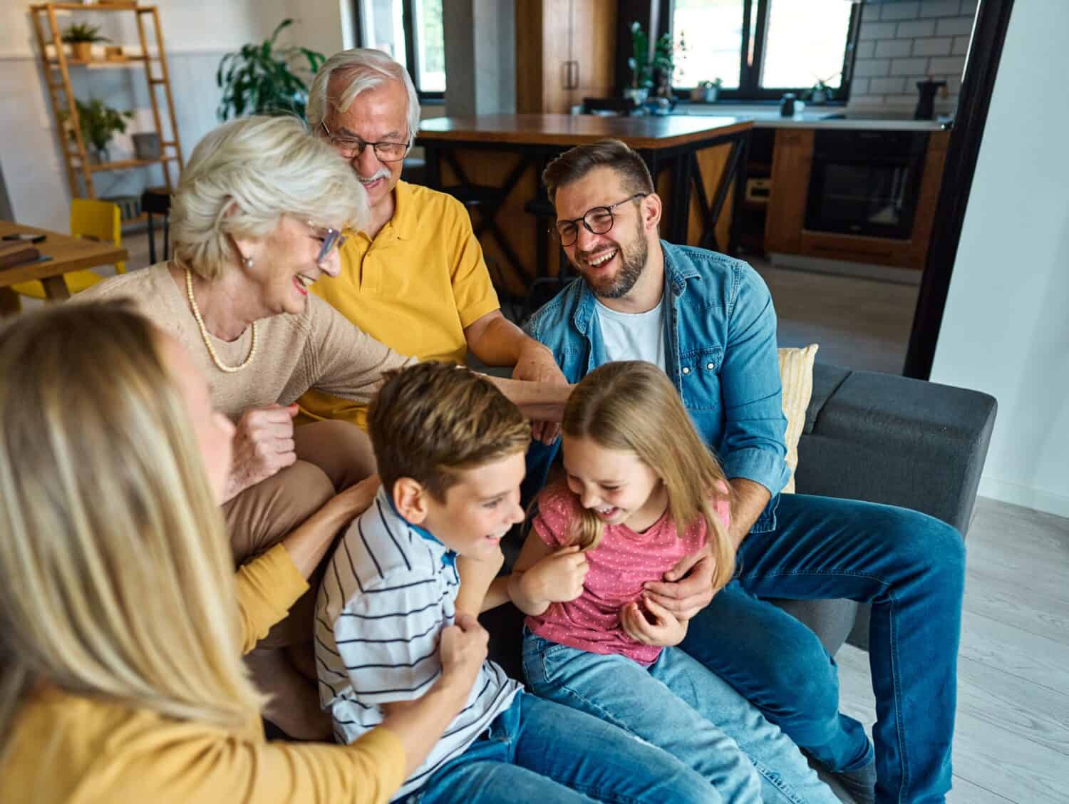 Portrait of a three generation famili, grandparents, parents and children sitting on sofa and having fun posing at home