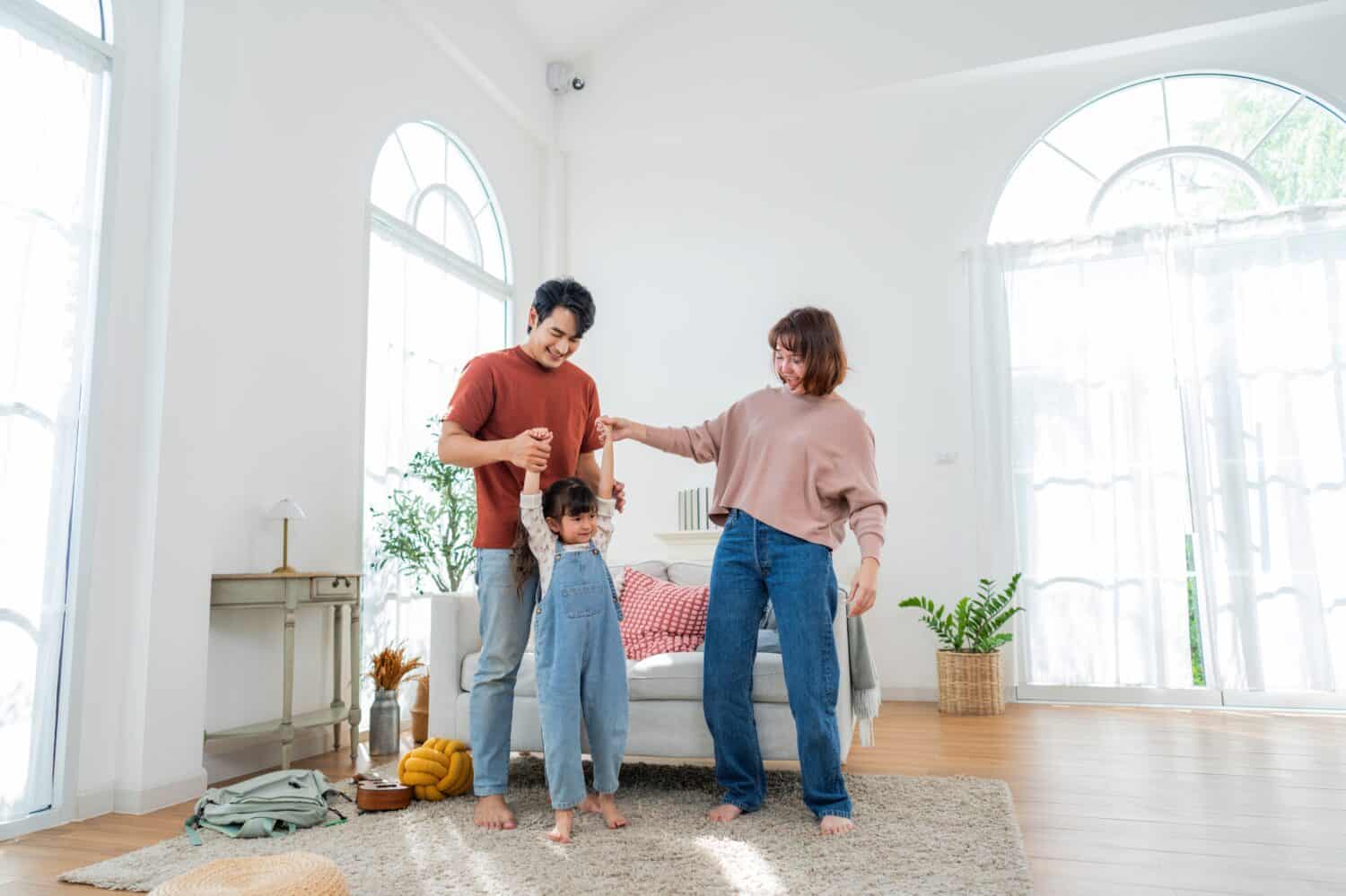A family is spending time together in their living room. They are playing and laughing with their child, creating happy moments on a weekend morning at home.