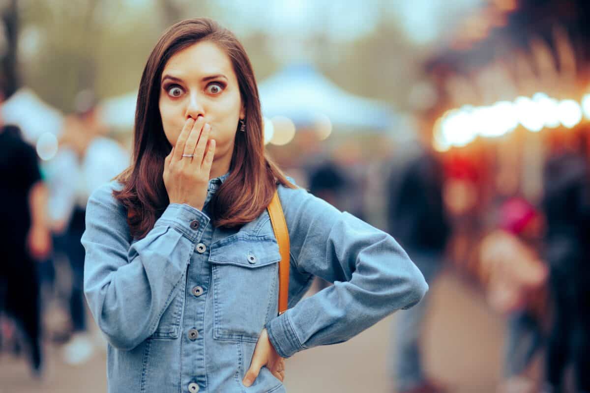 Woman feeling Sick Covering her Mouth at Local Funfair. Ill girl suffering from indigestion after eating some stress food