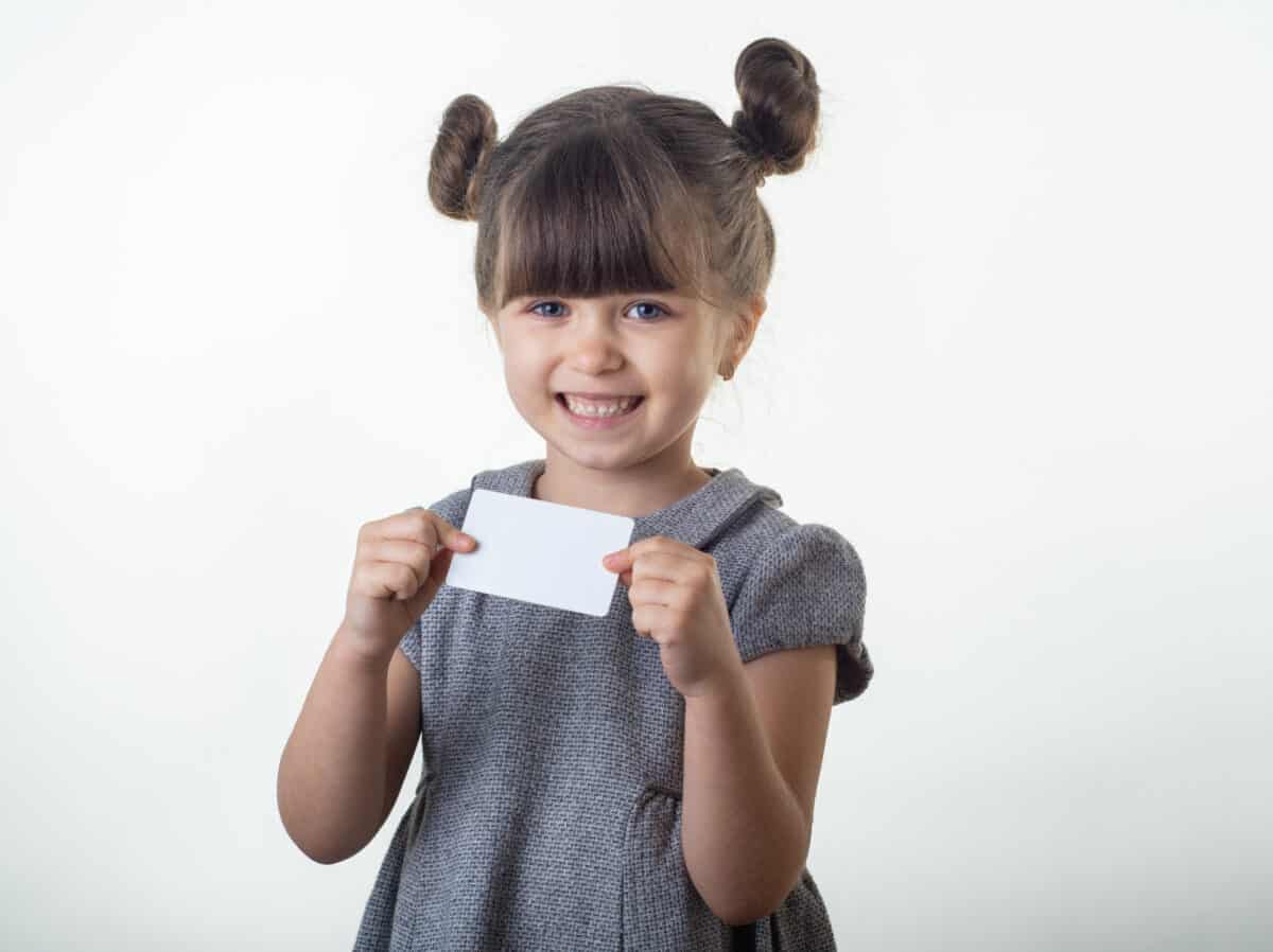 A little girl holding an index card.