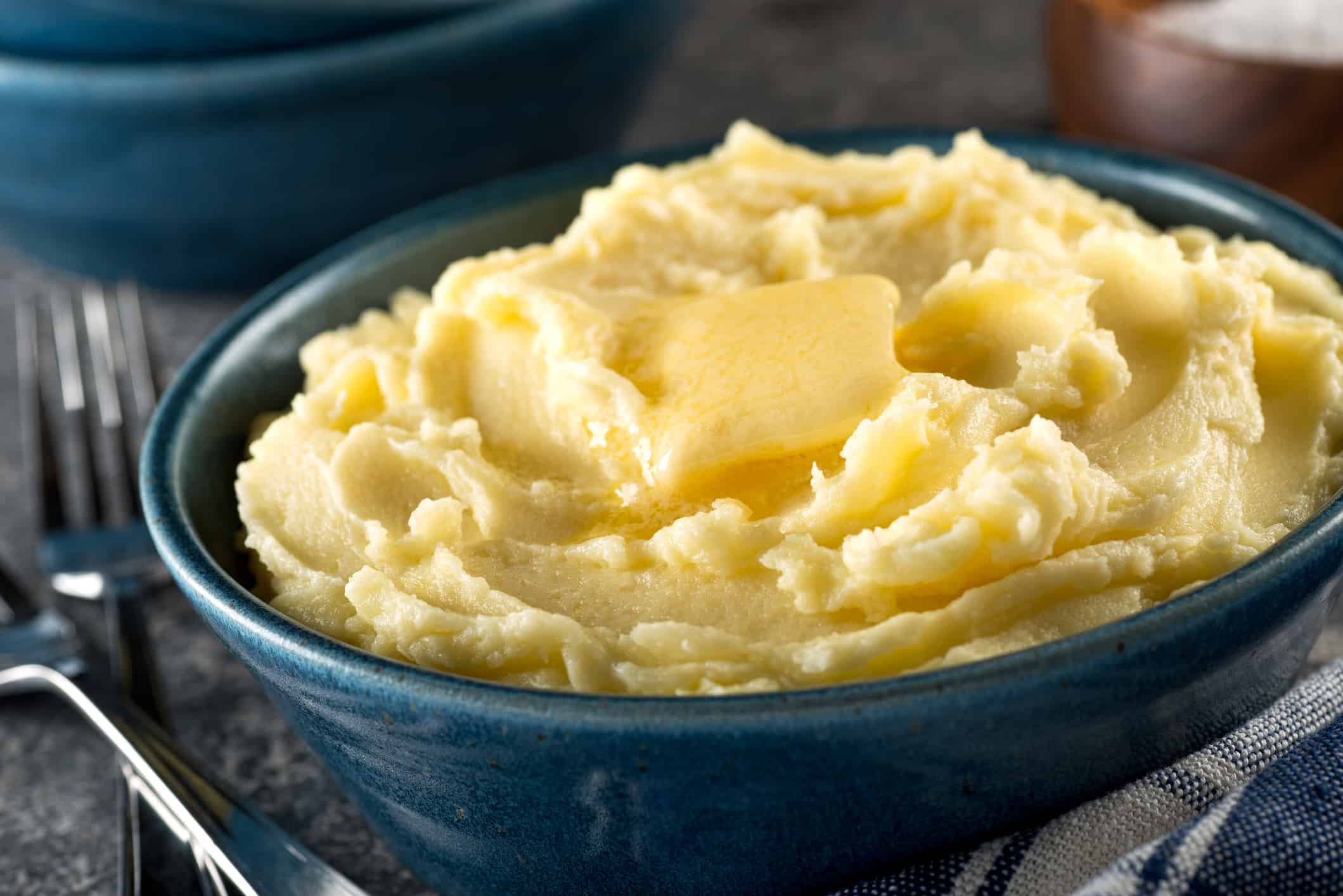 A bowl of delicious mashed potatoes with melted butter.