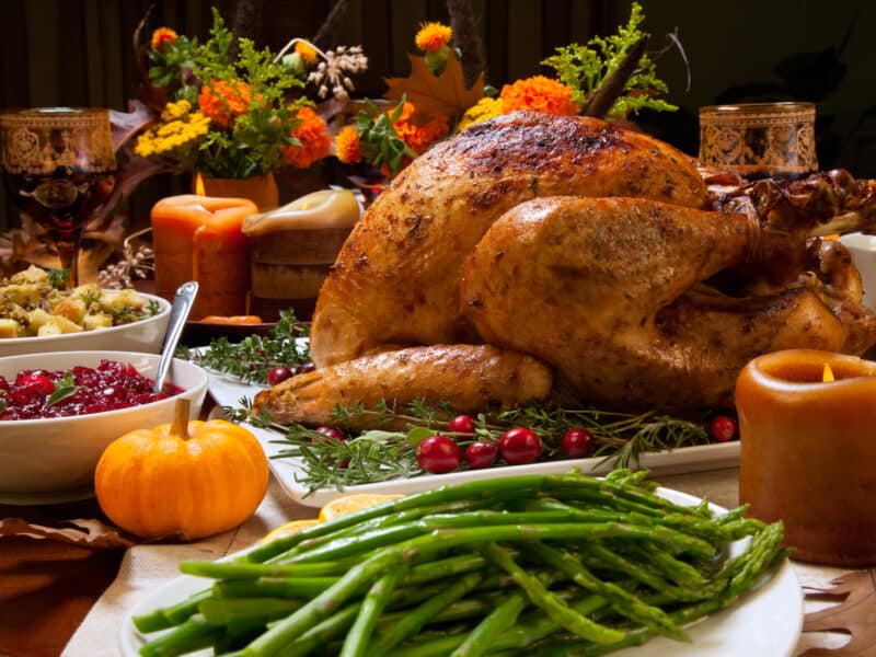 Roast Turkey with Herbal Rub on a holiday table with fresh green beans and mini pumpkin decor