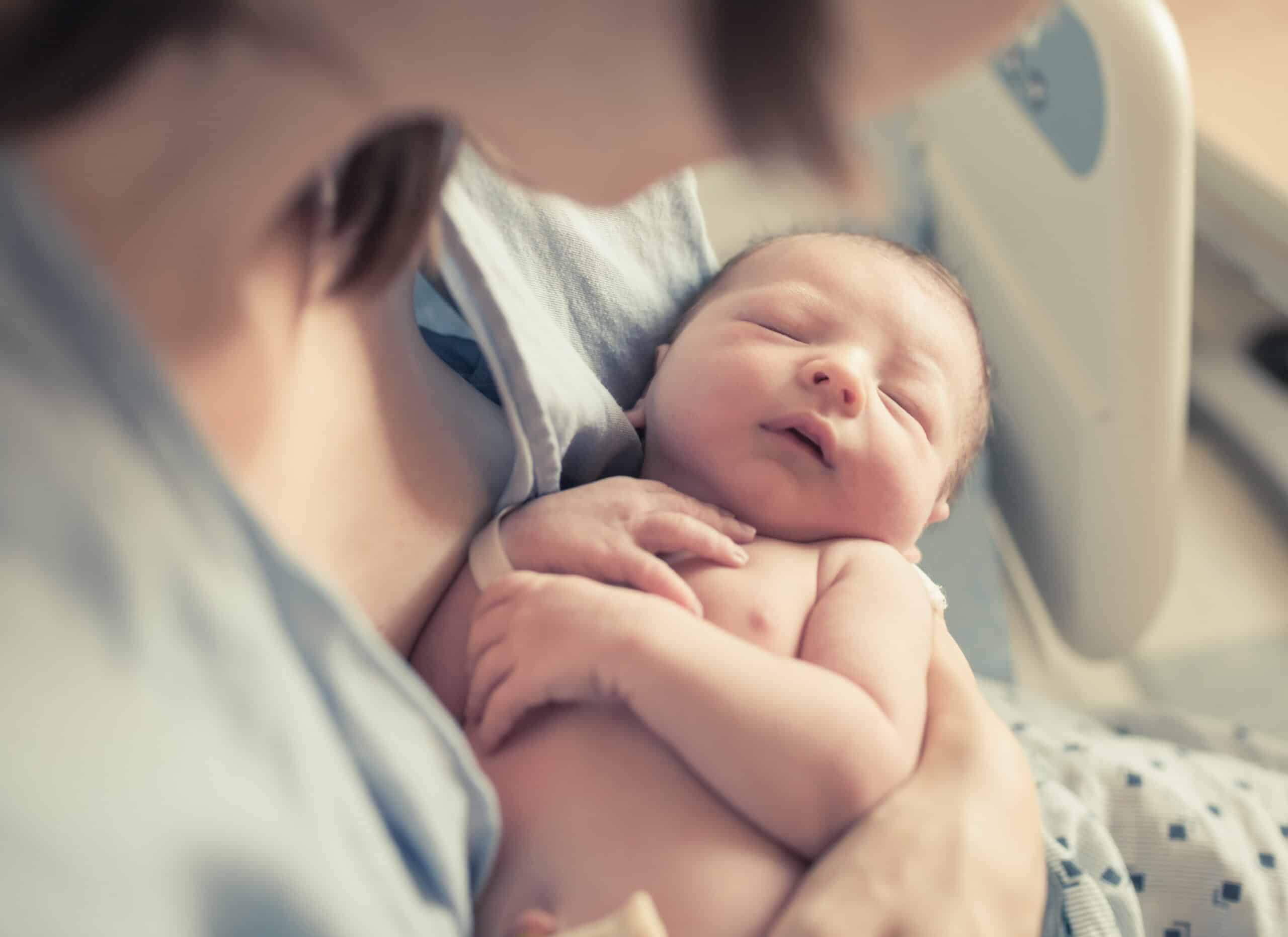 Newborn baby boy resting in mother's arms.