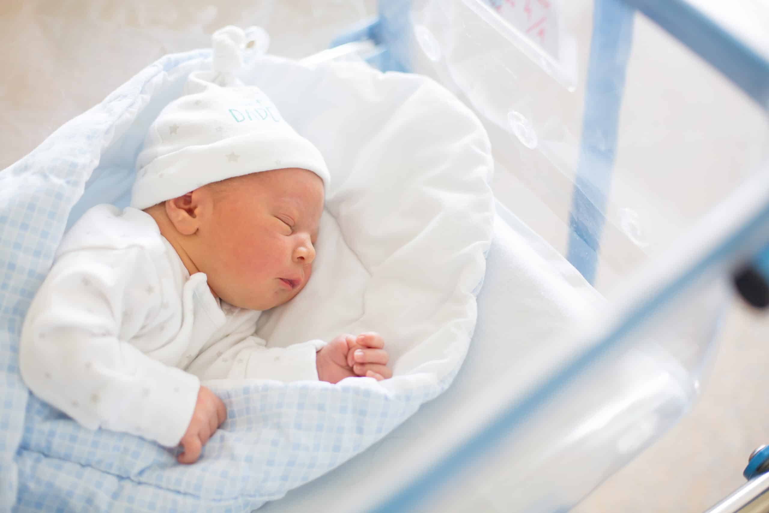 Beautiful newborn baby boy, laying in crib in prenatal hospital